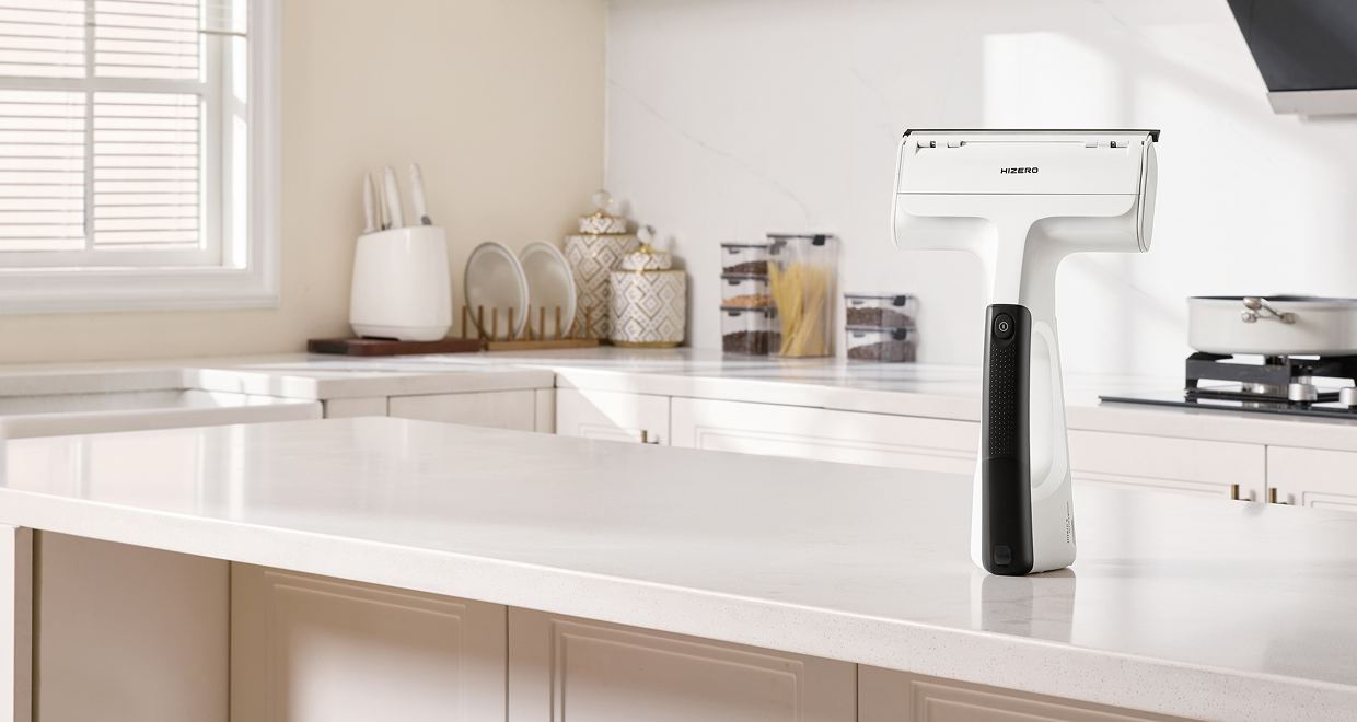White Hizero handheld cleaning device standing upright on a white kitchen island, with a bright, modern kitchen in the background.